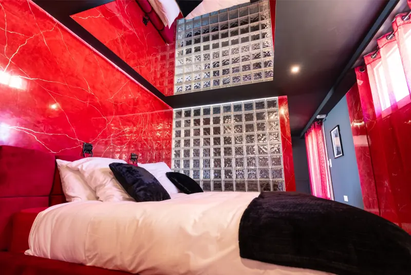 Lit king size aux coussins noirs et murs rouges laqués