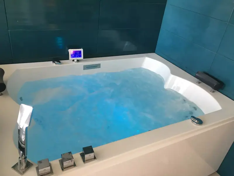 Baignoire balnéo dans une salle d’eau aux murs turquoise