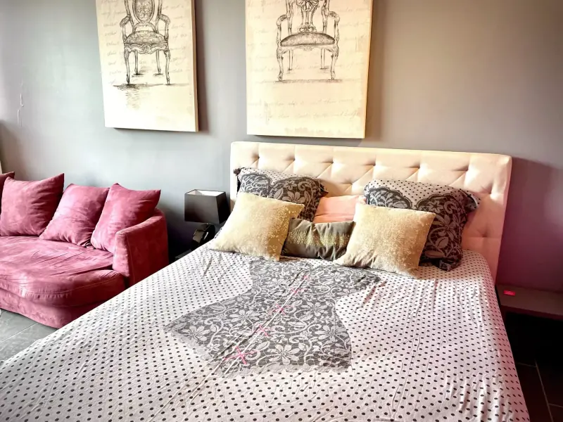 Chambre avec grand lit à tête capitonnée, coussins et tons rose poudré