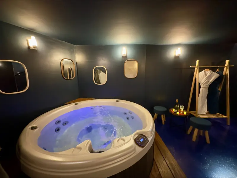 Jacuzzi rond dans la love room La Parenthèse, murs sombres et miroirs