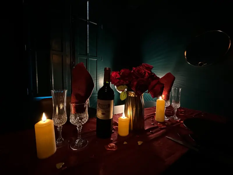 Bougies, roses rouges et vin sur une table de love room