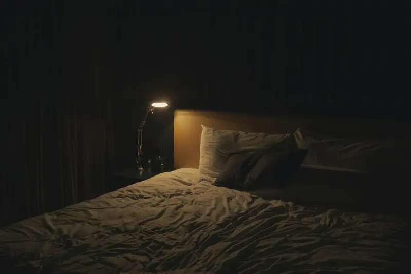Chambre d'hôtel tamisée, lampe de chevet allumée