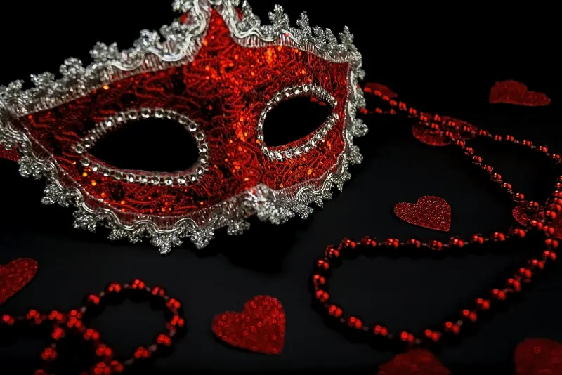 Masque de soirée rouge et perles sur fond sombre