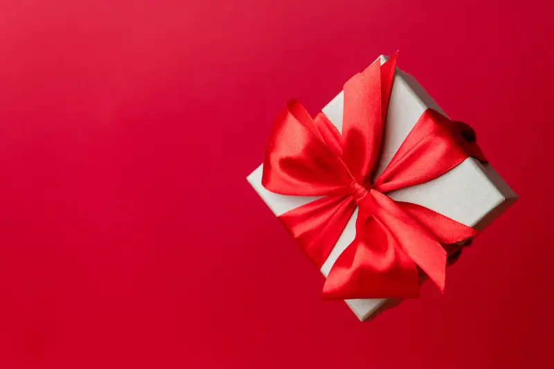 Petite boîte cadeau au ruban rouge sur fond rouge