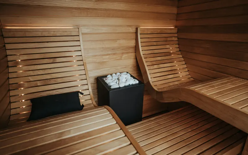 Sauna moderne en bois clair avec poêle à pierres