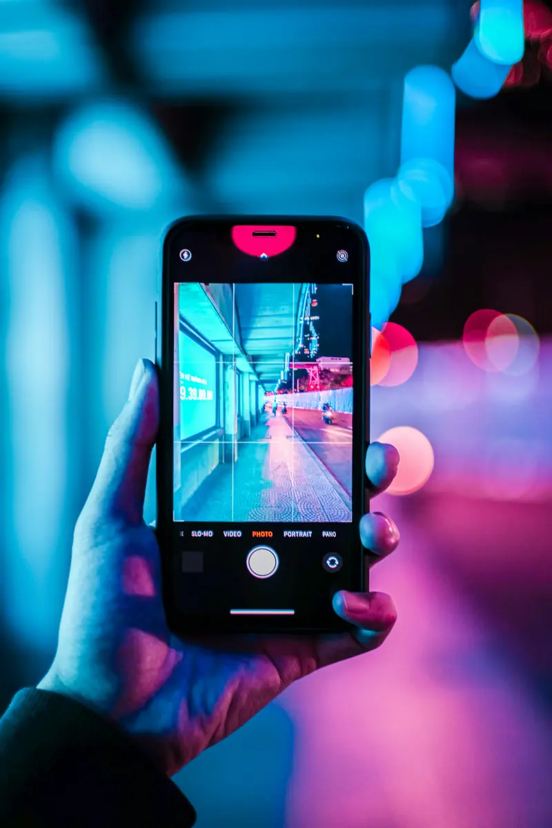 Smartphone tenu en main sous des lumières néon